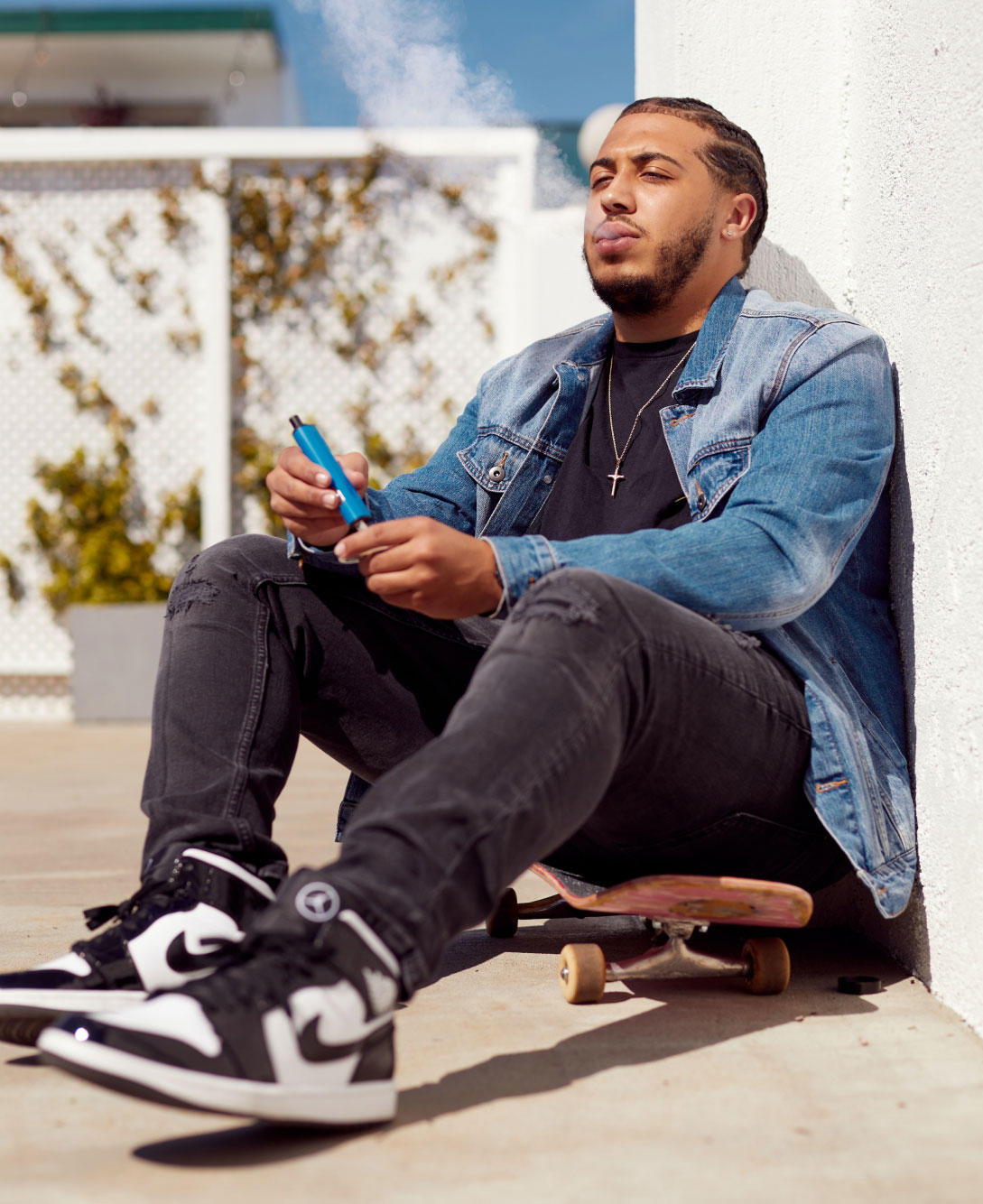 Man Sitting on Skateboard Vaping
